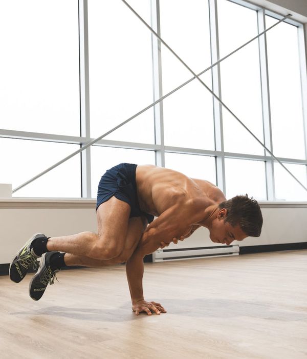 Man performing a controlled strength exercise in a minimalist dark room.